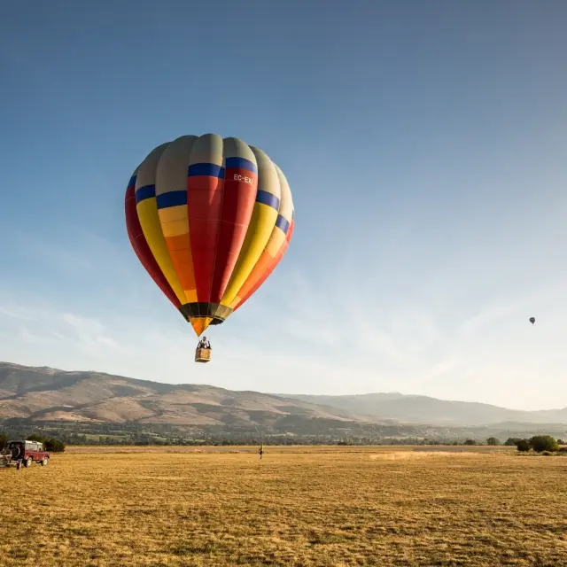 Montgolfière colorée en vol au-dessus de la plaine de Cerdagne, devant les montagnes.